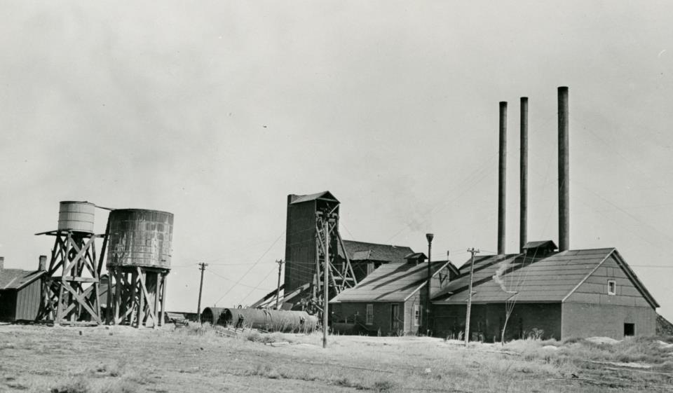 Black and white photo of coal mine buildings with smoke stacks