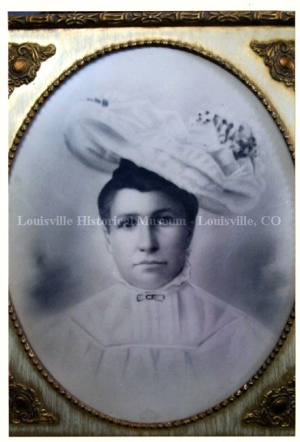 Historic photo of woman in very large hat and high collared blouse.