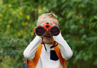 a young boy looks through colorful binoculars