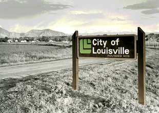 Landscape with mountains and "City of Louisville" sign