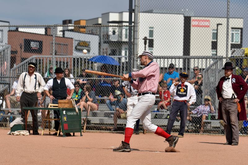 Baseball batter in vintage outfit swings in front of a crowd