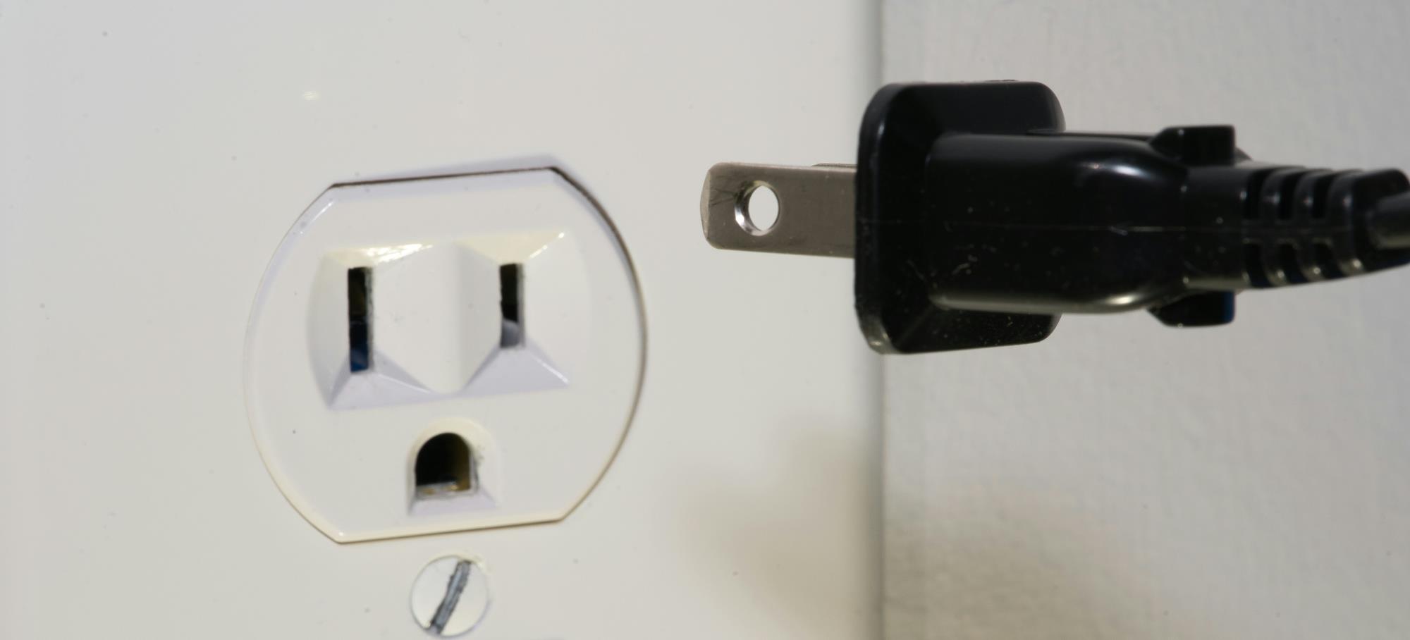 Electrical connector being plugged into an outlet.