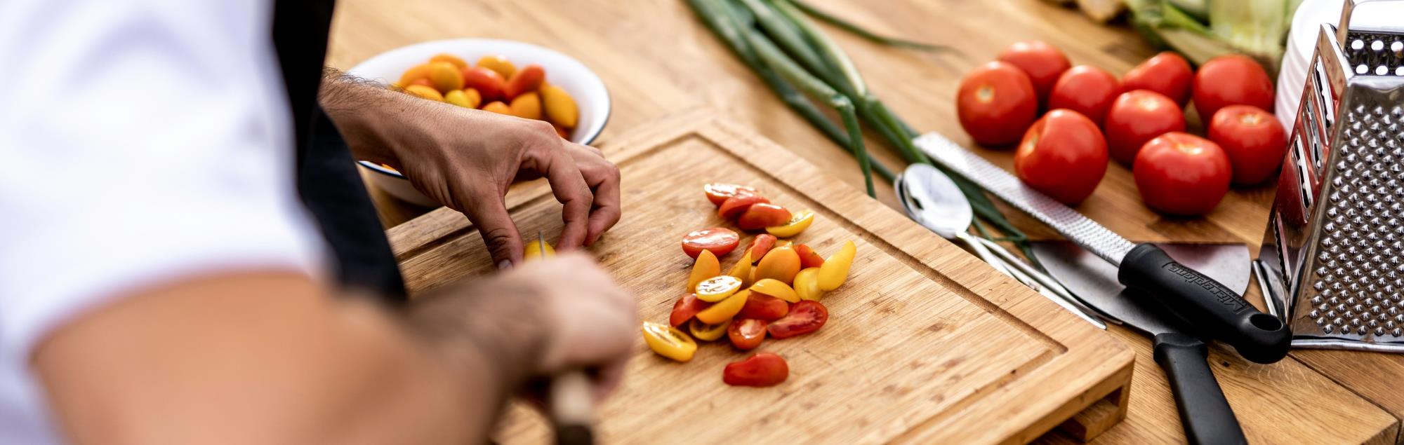 Close-up of chef cutting up vegetables on a cutting board.